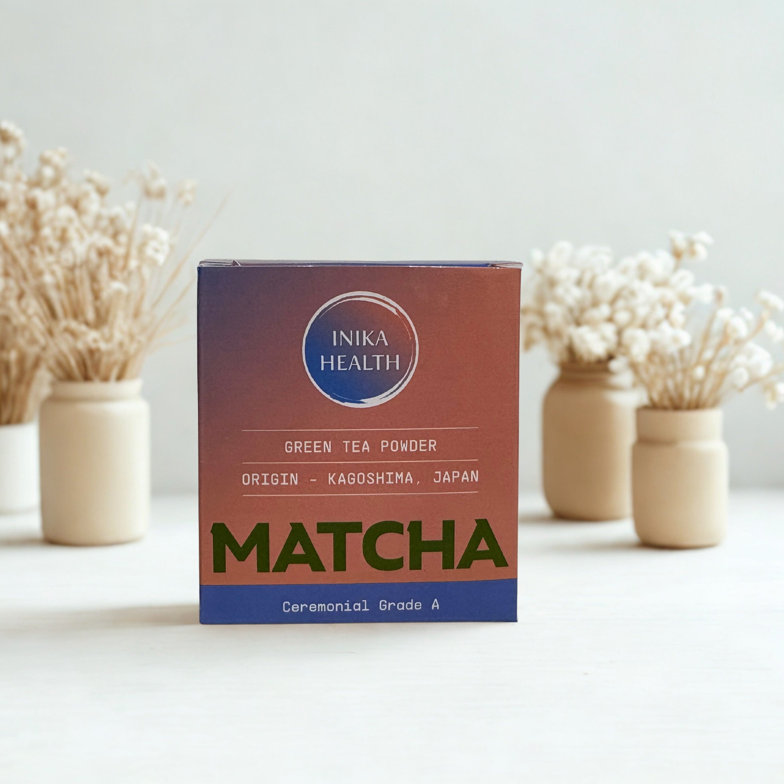 Box of Inika Health Matcha green tea powder on a white surface with decorative elements.