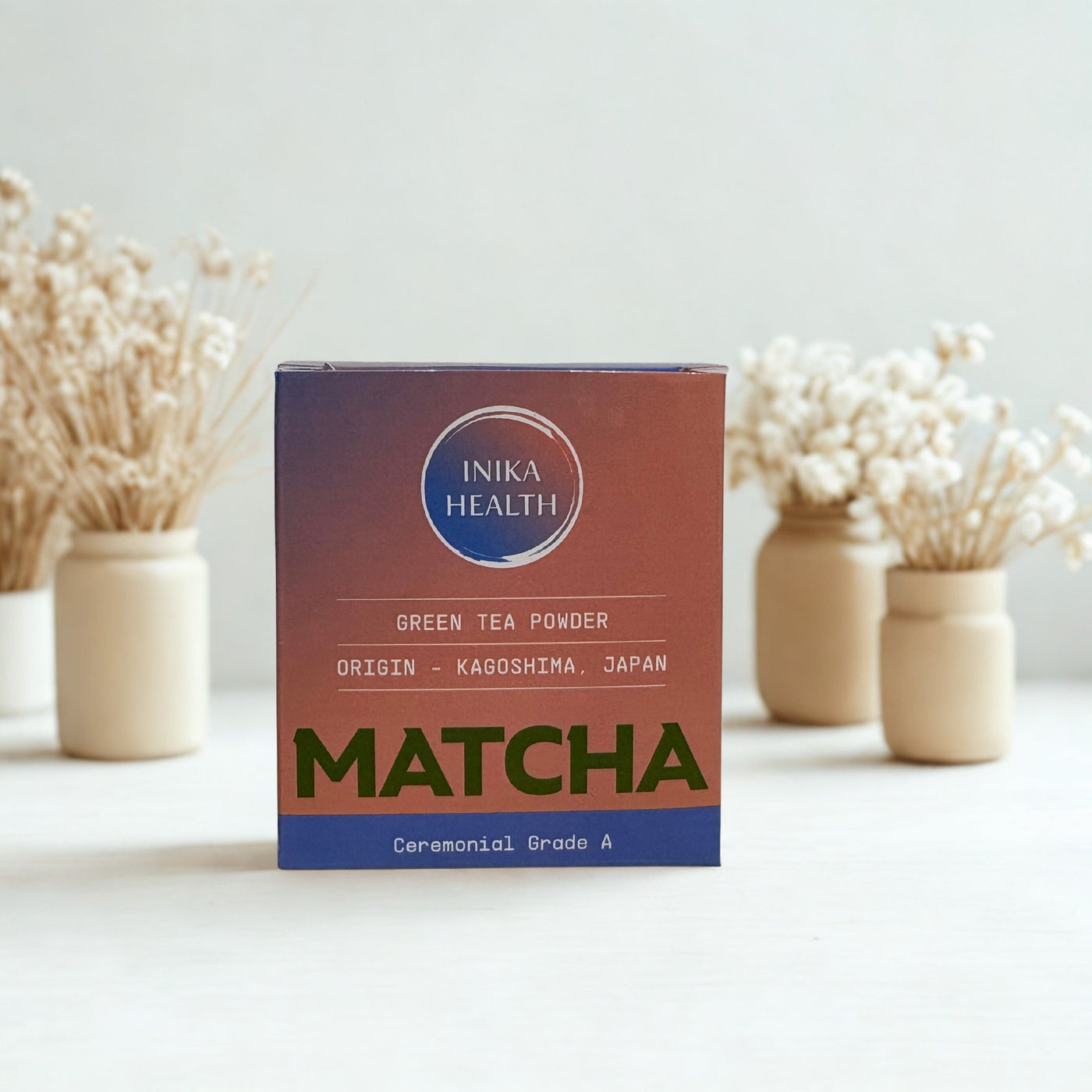 Box of Inika Health Matcha green tea powder on a white surface with decorative elements.
